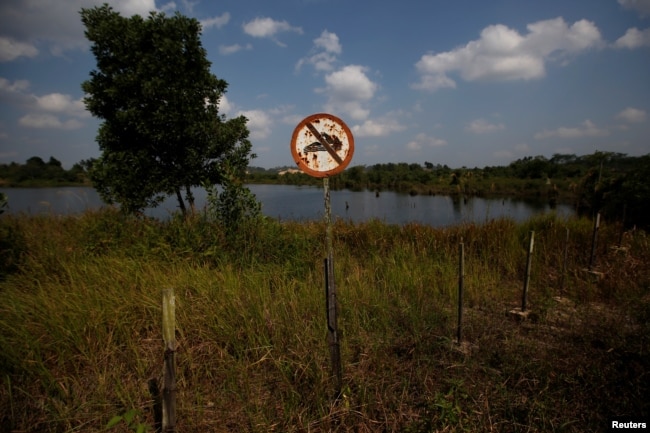 Tanda 'Dilarang Berenang" tampak di bekas lubang tambang batu bara yang terisi air di Kabupaten Kutai Kertanegara, Kalimantan Timur, 30 Agustus 2019. (Foto: Reuters)