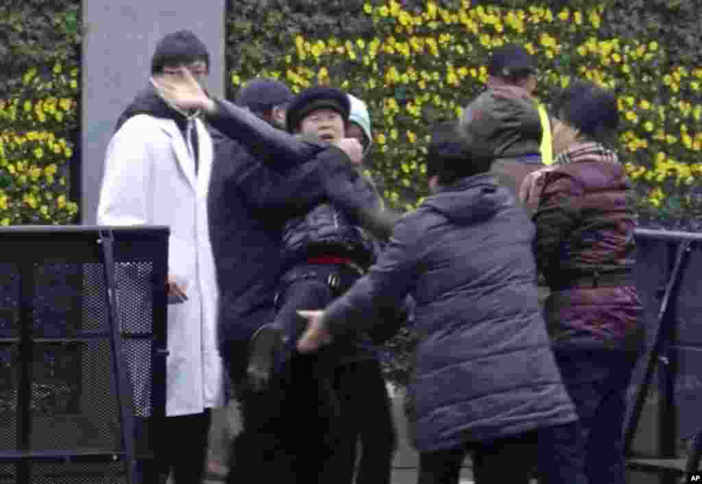 A New Year&#39;s Eve stampede victim reacts as she is taken away by officials at the site of a memorial ceremony for people who were killed in the tragic accident in Shanghai, China, Jan. 6, 2015.
