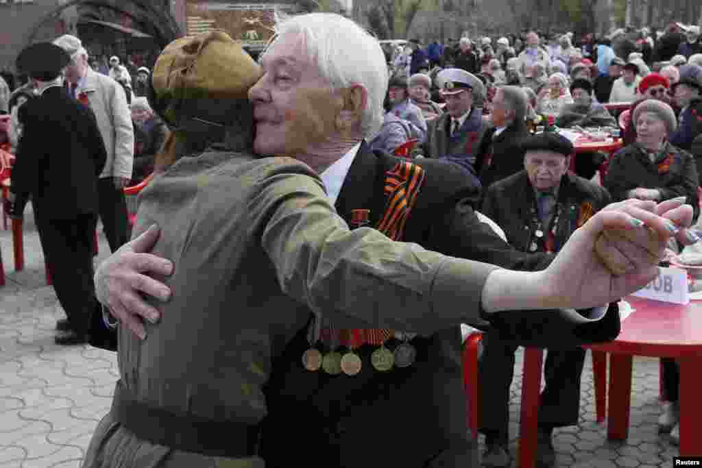 Seorang pria tua menari dengan seorang perempuan yang berpakaian militer dalam pertunjukan jalanan untuk menghormati veteran Perang Dunia II sebelum Hari Kemenangan di tengah kota Krasnoyarsk, Siberia Rusia. Rusia akan merayakan ulang tahun ke-70 kemenangan mereka atas Nazi Jerman pada Perang Dunia II pada 9 Mei.