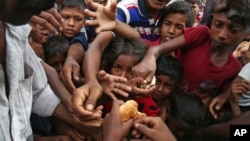 Rohingya children, who fled Myanmar, stretch their hands out to receive food distributed by locals at the Kutupalong makeshift refugee camp in Cox's Bazar, Bangladesh, Aug. 30, 2017.