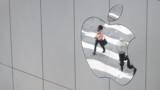 FILE - A woman is reflected in a Apple store logo in San Francisco, California, Aug. 21, 2017. 