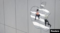 FILE - A woman is reflected in a Apple store logo in San Francisco, California, Aug. 21, 2017. 
