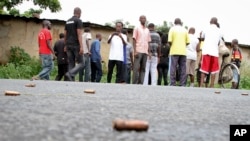 FILE - A man takes a picture of spent bullet casings lying on a street in the Nyakabiga neighborhood of Bujumbura, Burundi, Dec. 12, 2015.