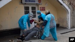 Para tenaga medis mengangkat pria yang terjatuh di luar Rumah Sakit Umum ke kursi roda untuk dibawa ke ruang gawat darurat bagi pasien Covid-19 di La Paz, Bolivia, 23 Juli 2020. (Foto: AP)