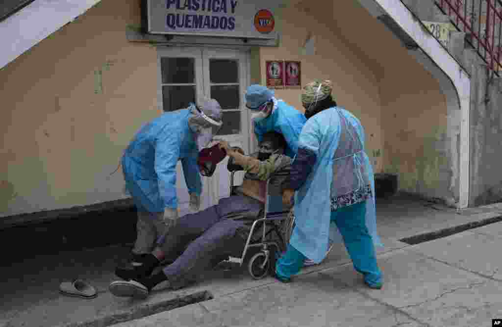 Healthcare workers lift a man who was lying on the ground outside the General Hospital into a wheelchair to be taken to the emergency room that treats people suspected of having COVID-19 in La Paz, Bolivia, Thursday, July 23, 2020.