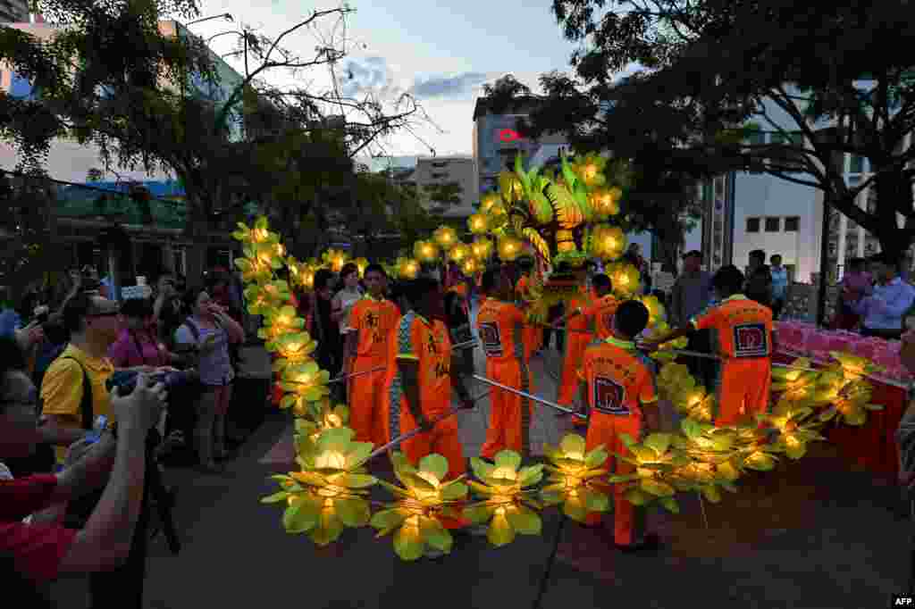 Local performers display dragon laterns during a media preview of the upcoming mid-autumn festival in Singapore.