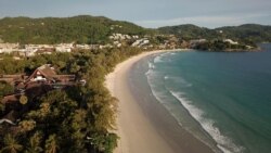 Orang-orang berjalan di pantai Kata yang hampir kosong saat Phuket dibuka kembali untuk turis asing, mengizinkan orang asing yang divaksinasi COVID-19 sepenuhnya untuk mengunjungi pulau resor tanpa karantina, di Phuket, Thailand 1 Juli 2021. Gambar diambi