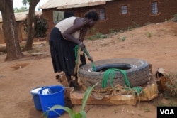 A woman draws water from an unprotected well in Chigwirizano, a peri-urban area hit by a Cholera outbreak in Malawi. (Photo: Lameck Masina for VOA)