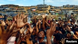 Rohingya refugees stretch their hands to receive aid distributed by local organisations at Balukhali makeshift refugee camp in Cox's Bazar, Bangladesh, September 14, 2017.