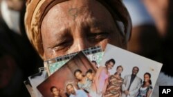 Ethiopian Israeli woman holds up pictures of relatives in Ethiopia during a demonstration in front of the Knesset, Israel's parliament, in Jerusalem, Monday, March 12, 2018. Hundreds of Ethiopian immigrants are protesting outside Israel's parliament, demanding the government fulfill a pledge to bring some 8,000 of their countrymen remaining in Ethiopia to Israel. 