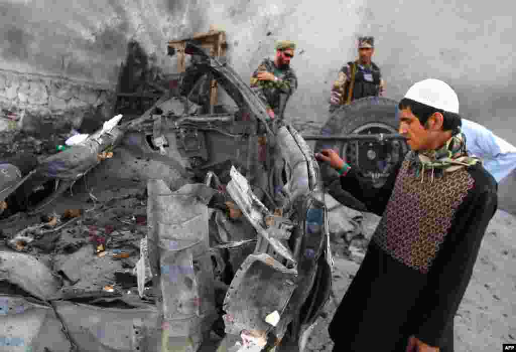 An Afghan man examines the remains of a car after three suicide bombers were killed before they reached Jalalabad airport, which security forces say was their target, in Jalalabad, April 15, 2012. (AP)