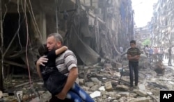 In this image made from video and posted online from Validated UGC, a man carries a child after airstrikes hit Aleppo, Syria, April 28, 2016.