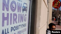 FILE - A "Now Hiring" sign sits in the window of Insomnia Cookies in Cambridge, Massachusetts, Feb. 11, 2019. 