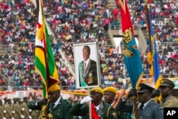Soldiers carry a portrait of Zimbabwe's President Robert Mugabe during the country's 37th Independence celebrations in Harare, April, 18, 2017.