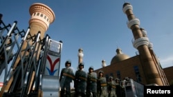 Cảnh sát bán quân sự Trung Quốc trong trang phục chống bạo động canh gác tại lối vào đền thờ Hồi giáo ở trung tâm thành phố Urumqi, Tân Cương.