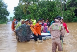 Foto Badan Nasional Penanggulangan Bencana Indonesia (BNPB) ini menunjukkan para penyelamat mengevakuasi penduduk desa dengan perahu karet di daerah banjir di kabupaten Tanah Laut, Kalimantan Selatan, 15 Januari 2021. (Foto: BNPB via AFP)