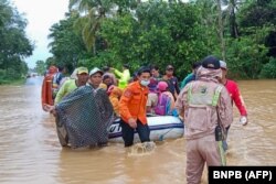 Foto Badan Nasional Penanggulangan Bencana Indonesia (BNPB) ini menunjukkan para penyelamat mengevakuasi penduduk desa dengan perahu karet di daerah banjir di kabupaten Tanah Laut, Kalimantan Selatan, 15 Januari 2021. (Foto: BNPB via AFP)