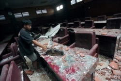 Seorang pria membersihkan ruang sidang yang rusak akibat gempa bumi yang melanda laut 91 km tenggara Blitar, foto di Blitar, Jawa Timur, 10 April 2021. (Foto: Antara/Irfan Anshori via Reuters)