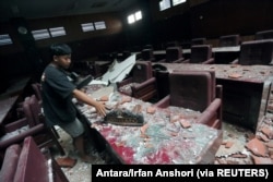 Seorang pria membersihkan ruang sidang yang rusak akibat gempa bumi yang melanda laut 91 km tenggara Blitar, foto di Blitar, Jawa Timur, 10 April 2021. (Foto: Antara/Irfan Anshori via Reuters)