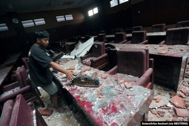 Seorang pria membersihkan ruang sidang yang rusak akibat gempa bumi yang melanda laut 91 km tenggara Blitar, foto di Blitar, Jawa Timur, 10 April 2021. (Foto: Antara/Irfan Anshori via Reuters)