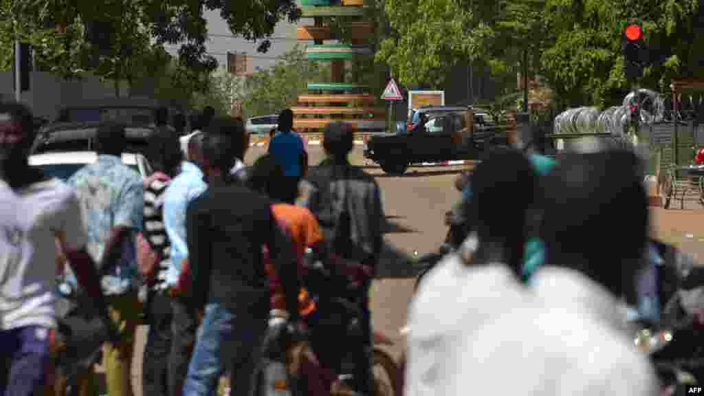 Les passants regardent une épaisse colonne de fumée noire au niveau de l&#39;état-major des armées à Ouagadougou, Burkina Faso, le 2 mars 2018.