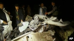 Pemberontak Syiah Houthi mengelilingi bangkai mobil di lokasi serangan bom mobil di Sana'a, Yaman (17/6). (AP/Osamh Abdulrhman)