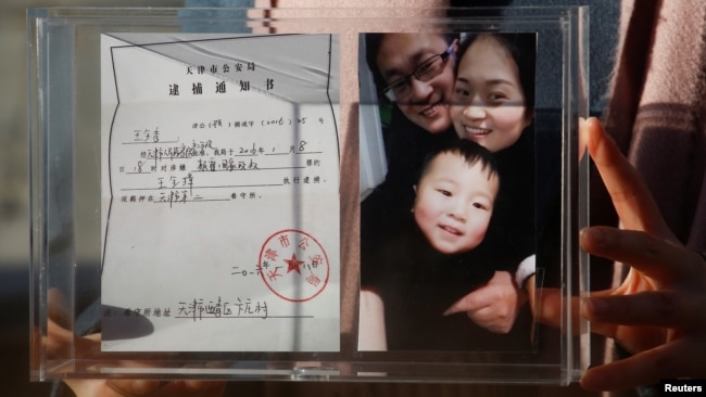 中国人权律师王全璋的妻子李文足展示全家人的照片与天津公安局的逮捕通知书。(2018年12月17日)