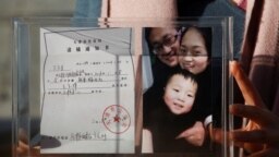 资料照：中国维权律师王全璋的妻子李文足手举全家福照片和天津警方的逮捕通知书。（2018年12月17日）