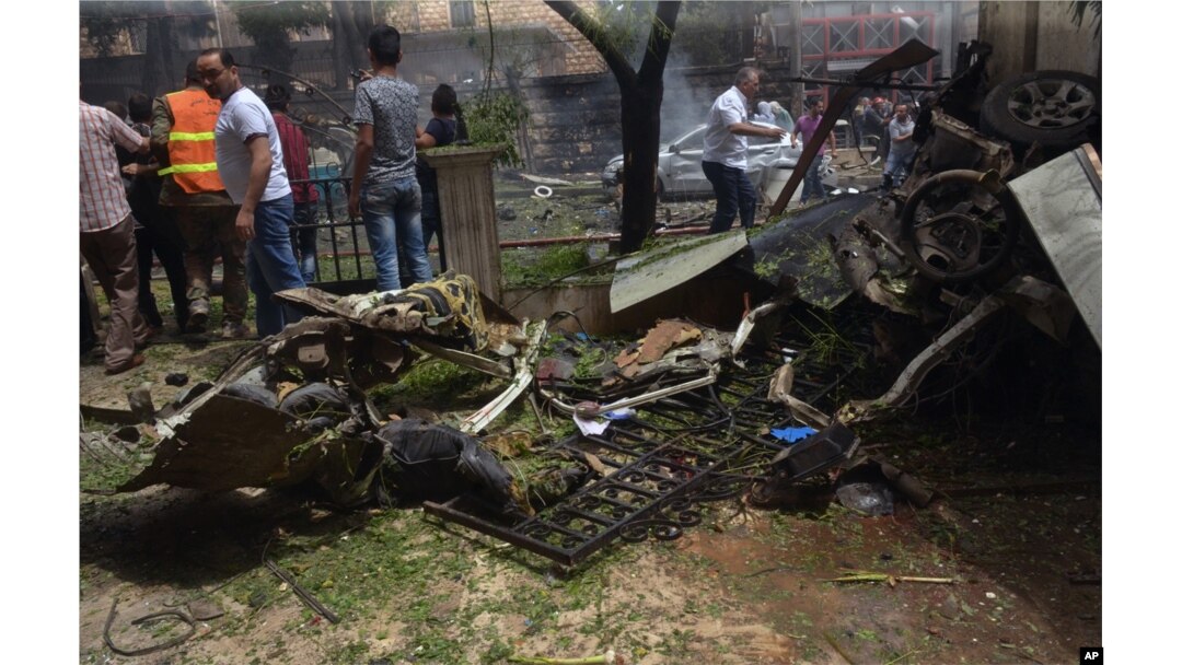 FILE - In this photo released by the Syrian official news agency SANA, Syrian citizens and firefighters gather where a rocket hit the Dubeet hospital in the central neighborhood of Muhafaza in Aleppo, Syria, May 3, 2016.