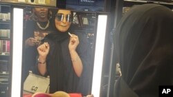 In this Thursday, April 19, 2018 photo, Bahraini singer Jihan Sheib tries on a shade of blue lipstick from Rihanna's new Fenty line that debuted across the kingdom in Sephora stores in Riyadh, Saudi Arabia. Here, where most women cover their faces and hai