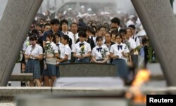 Para pengunjung berdoa untuk para korban bom atom di depan monumen untuk para korban pengeboman atom 1945 di Taman Monumen Perdamaian Hiroshima, di barat Jepang, 6 Agustus 2019. (Foto: Reuters)