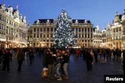 Tourists take a selfie in front of a Christmas tree on Brussels' Grand Place, Dec. 31, 2015, after Belgian police held three people for questioning, as part of an investigation into an alleged plot to carry out an attack in the capital on New Year's Eve.