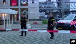 In this image taken from video, officers stand behind a cordoned-off area in Rotterdam, Aug. 23, 2017, after a concert by an American band was canceled following a possible terror threat.