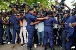 FILE - Congolese police officers hold back members of the media as Congo opposition candidate Martin Fayulu leaves the constitution court in Kinshasa, Congo, Jan. 12, 2019.