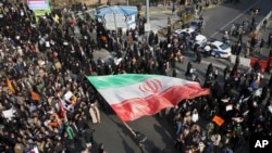 Manifestan pwo-gouvënmantal avèk yon gwo drapo iranyen nan men yo nan yon meeting ki deoule nan vil Mashhad, nan pati nòdès Iran. (Foto: Tasnim News Agency, 4 janvye 2018) 