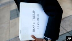 FILE - Omar Jadwat, director of the ACLU's Immigrants' Rights Project, carries court documents after a news conference outside a federal courthouse in Greenbelt, Md., Oct. 16, 2017, following a hearing regarding three lawsuits over the Trump administration's restrictions on travelers from certain countries.