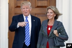 Then-President-elect Donald Trump, left, and Betsy DeVos, right, pose for photographs at Trump National Golf Club Bedminster's clubhouse in Bedminster, N.J.