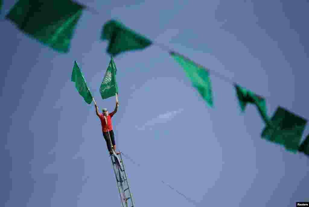 Bunting hangs as a Palestinian holds flags on a ladder at a rally marking the 34th anniversary of Hamas&#39; founding, in the northern Gaza Strip.