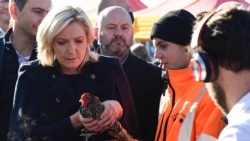 French presidential candidate Marine Le Pen (L) holds a chicken at the agricultural fair in Poussay, eastern France on Oct. 23, 2021.