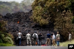 Members of the media record a wall of lava entering the ocean near Pahoa, Hawaii, Sunday, May 20, 2018.
