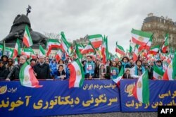 People hold a banner and wave former Iranian flags during a demonstration of the exiled Iranian opposition to protest against the celebration in Iran of the 40th anniversary of the Islamic Revolution, Feb. 8, 2019 in Paris, France.