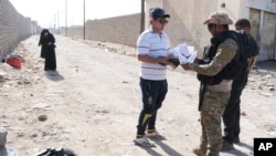 A man who identified himself as Omar Danoun, who claimed to be from Mosul, has his papers checked and is taken into custody by Iraqi soldier in Gogjali, Iraq, Nov. 12, 2016.