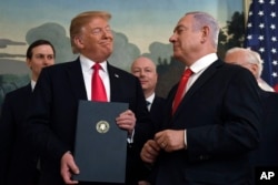 President Donald Trump smiles at Israeli Prime Minister Benjamin Netanyahu, right, after signing an official proclamation formally recognizing the Golan Heights as part of Israel, at the White House in Washington, March 25, 2019.