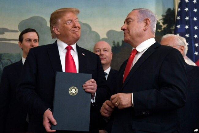 President Donald Trump smiles at Israeli Prime Minister Benjamin Netanyahu, right, after signing a proclamation in the Diplomatic Reception Room at the White House in Washington, Monday, March 25, 2019.