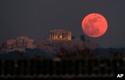 A super blue blood moon rises behind the 2,500-year-old Parthenon temple on the Acropolis of Athens, Greece, Jan. 31, 2018.