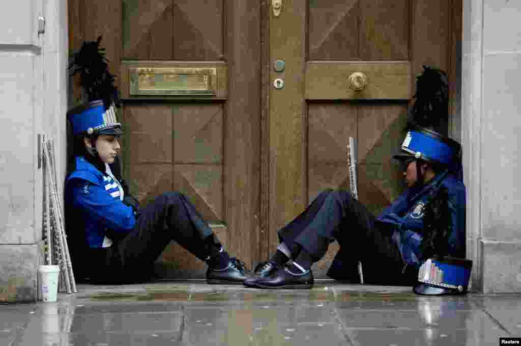 Members of a marching band shelter from the rain before performing at the 28th annual New Year's Day parade in London.