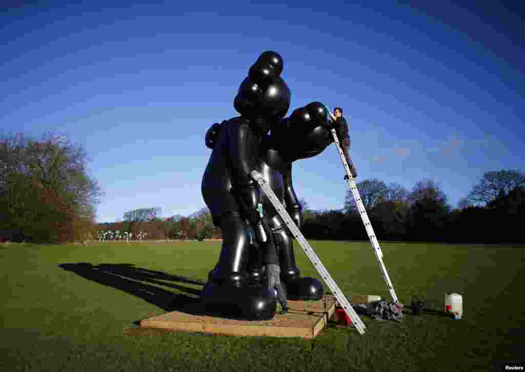 Workers clean a sculpture entitled &quot;Along The Way&quot; by American artist Kaws at the Yorkshire Sculpture Park in Wakefield, Britain.