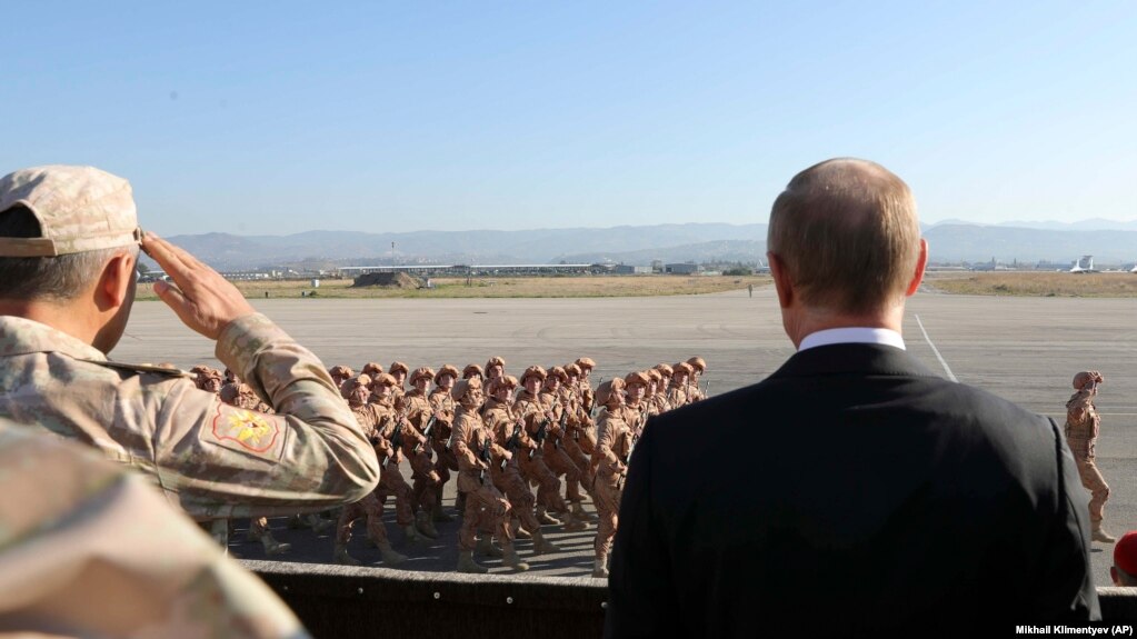 Tổng thống Nga Vladimir Putin (phải) nhìn binh sĩ diễu hành khi ông và Tổng thống Syria Bashar al-Assad thăm căn cứ không quân Hemeimeem ở syria, ngày 12 tháng 12, 2017.