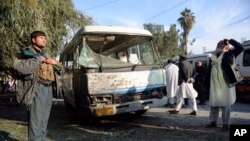 FILE - An Afghan security policeman stands guard near a damaged bus after a suicide attack in Nangarhar province east of Kabul, Afghanistan, Nov. 23, 2017. 