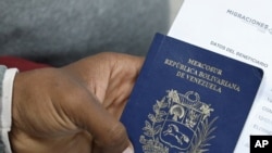 ARCHIVO-Migrante venezolano sostiene su pasaporte en una fila para obtener un permiso de residencia temporal frente a la oficina de inmigración en Lima, Perú, el 20 de agosto de 2018.